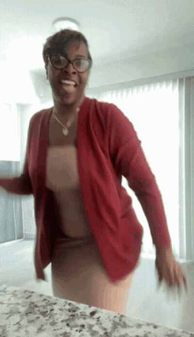 A Woman Wearing Glasses And A Red Cardigan Dancing GIF