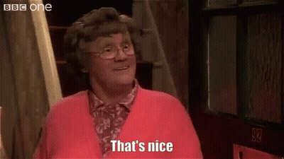 A Woman Wearing Glasses And A Red Sweater Is Standing In Front Of A Door And Says `` That 'S Nice '' . GIF