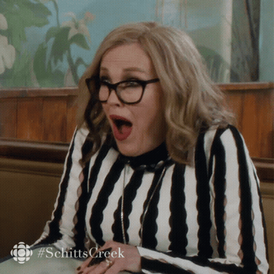 A Woman Wearing Glasses And A Striped Shirt With #Schittscreek Written On The Bottom GIF