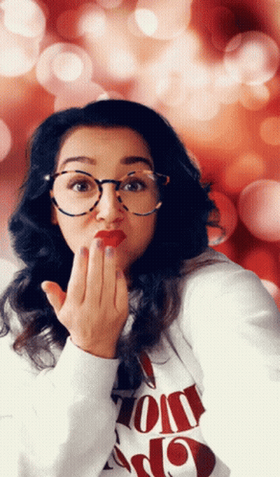A Woman Wearing Glasses And A Sweater That Says ' I Love You ' On It Blows A Kiss GIF