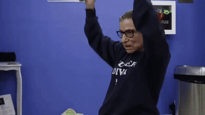 A Woman Wearing Glasses And A Sweatshirt That Says " Car Diva " Is Dancing In A Room . GIF
