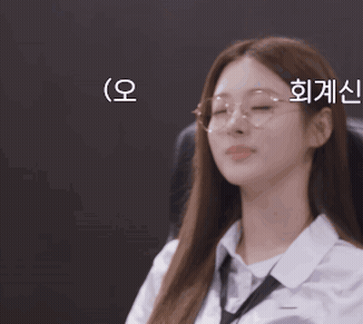 A Woman Wearing Glasses And A White Shirt Is Sitting In A Chair GIF