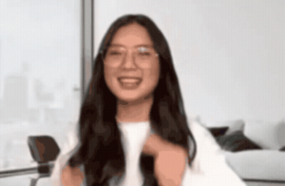 A Woman Wearing Glasses And A White Shirt Smiles For The Camera GIF