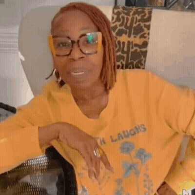 A Woman Wearing Glasses And A Yellow Shirt That Says Birth Laughs . GIF