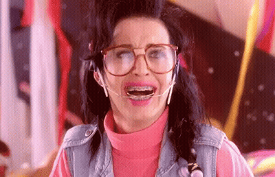 A Woman Wearing Glasses And Braces Is Making A Face . GIF