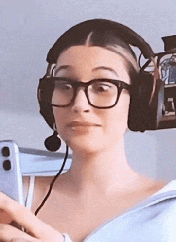 A Woman Wearing Glasses And Headphones Is Holding A Cell Phone GIF