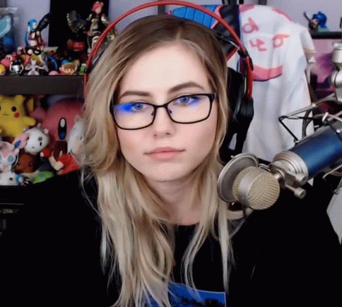A Woman Wearing Glasses And Headphones Is Sitting In Front Of A Microphone GIF