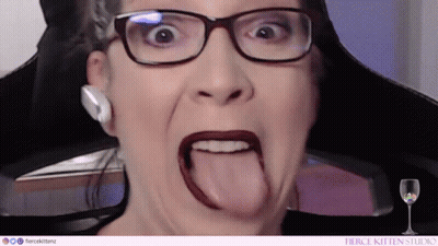 A Woman Wearing Glasses And Red Lipstick Is Sticking Her Tongue Out . GIF