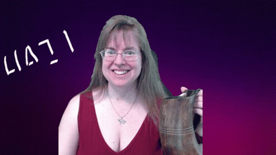 A Woman Wearing Glasses Holds A Brown Boot In Front Of A Purple Background That Says Lia71 GIF
