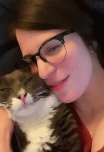 A Woman Wearing Glasses Holds A Cat In Her Lap GIF