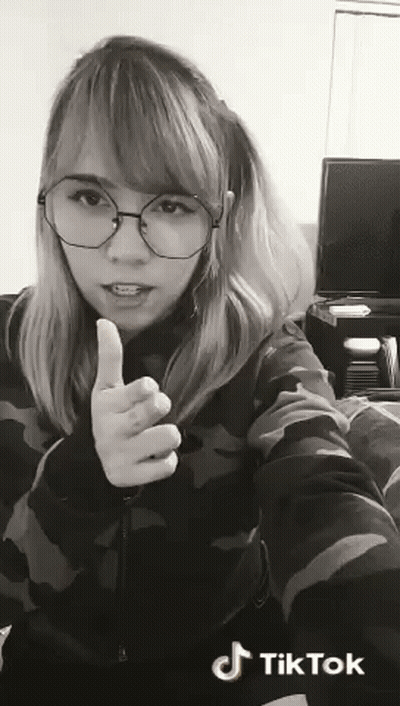 A Woman Wearing Glasses Is Giving A Thumbs Up Sign In A Black And White Photo . GIF