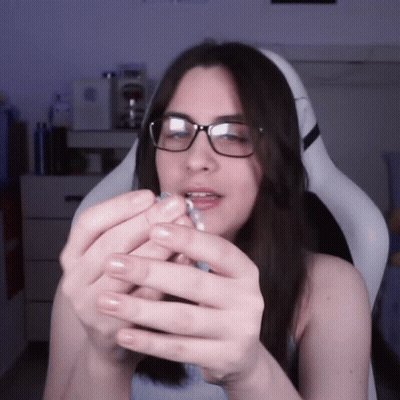 A Woman Wearing Glasses Is Holding A Blue Object In Her Hands GIF