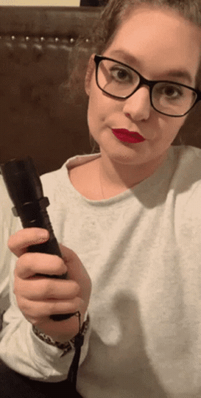 A Woman Wearing Glasses Is Holding A Flashlight In Her Hand GIF