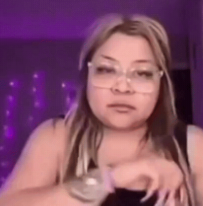 A Woman Wearing Glasses Is Making A Funny Face And Looking At The Camera . GIF