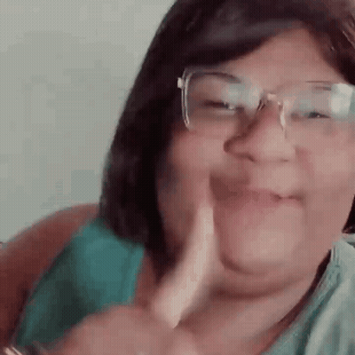 A Woman Wearing Glasses Is Making A Funny Face While Giving A Thumbs Up . GIF
