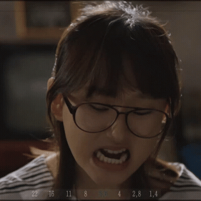 A Woman Wearing Glasses Is Making A Funny Face While Holding A Fork In Her Hand .. GIF