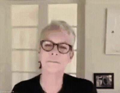 A Woman Wearing Glasses Is Making A Funny Face While Standing In Front Of A Window . GIF