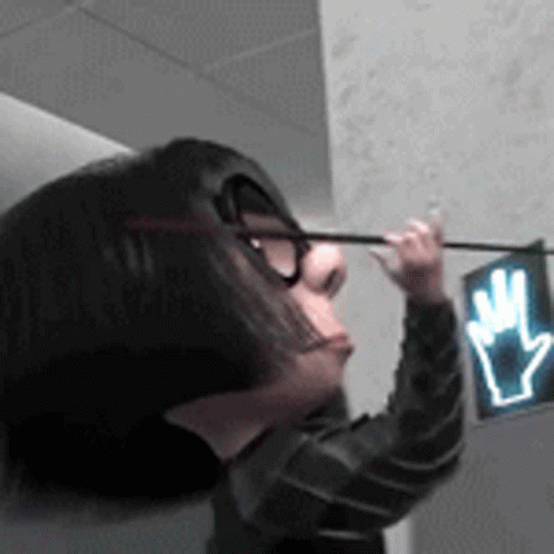 A Woman Wearing Glasses Is Pointing At A Hand Sign GIF