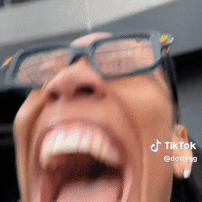 A Woman Wearing Glasses Is Screaming With Her Mouth Open . GIF