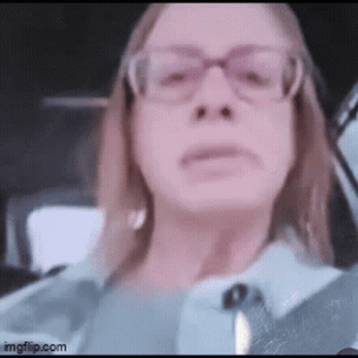 A Woman Wearing Glasses Is Sitting In A Car And Looking At The Camera . GIF