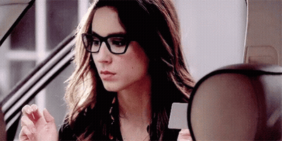 A Woman Wearing Glasses Is Sitting In A Car . GIF