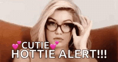 A Woman Wearing Glasses Is Sitting In A Chair And Holding A Pair Of Glasses . GIF
