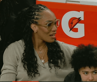 A Woman Wearing Glasses Is Sitting In Front Of A Gatorade Cooler GIF