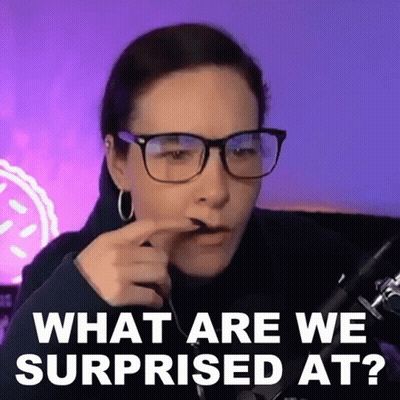 A Woman Wearing Glasses Is Sitting In Front Of A Microphone And Making A Surprised Face . GIF