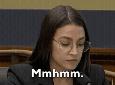 A Woman Wearing Glasses Is Sitting In Front Of A Microphone . GIF