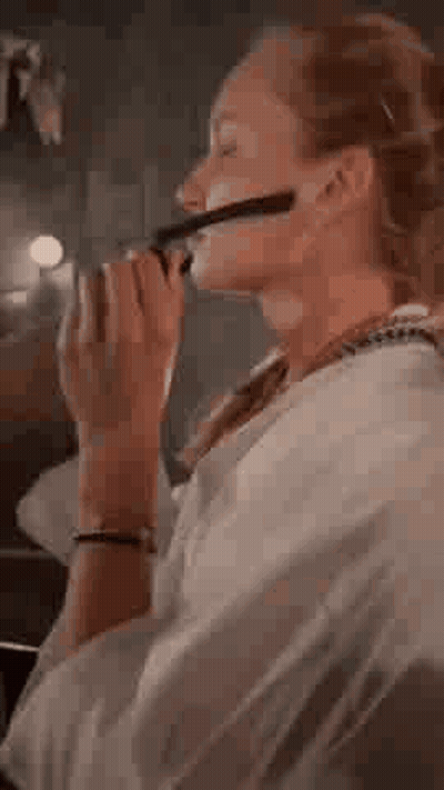 A Woman Wearing Glasses Is Sitting On A Couch And Looking Through A Pair Of Binoculars . GIF