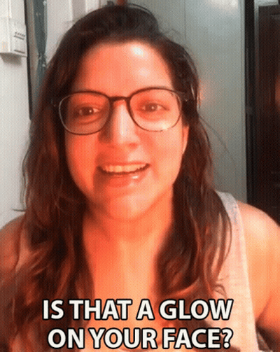 A Woman Wearing Glasses Is Smiling And Asking If There Is A Glow On Her Face GIF