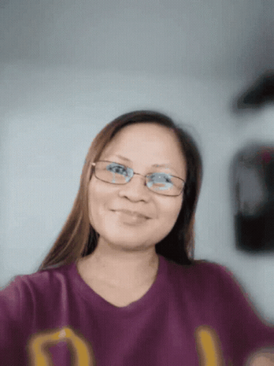A Woman Wearing Glasses Is Smiling And Wearing A Purple Shirt With The Letter D On It GIF