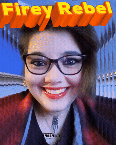 A Woman Wearing Glasses Is Smiling In Front Of A Poster That Says Firey Rebel GIF