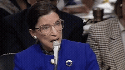 A Woman Wearing Glasses Is Speaking Into A Microphone GIF