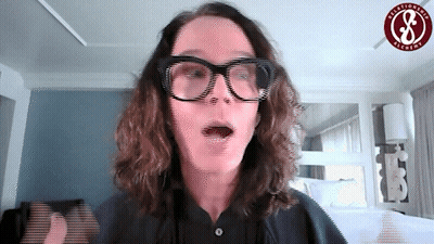 A Woman Wearing Glasses Is Standing In Front Of A Sign That Says ' California ' On It GIF