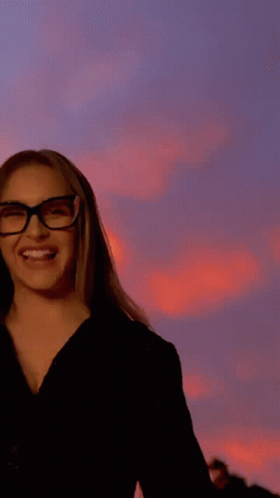 A Woman Wearing Glasses Is Sticking Out Her Tongue . GIF