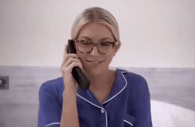 A Woman Wearing Glasses Is Talking On A Phone . GIF