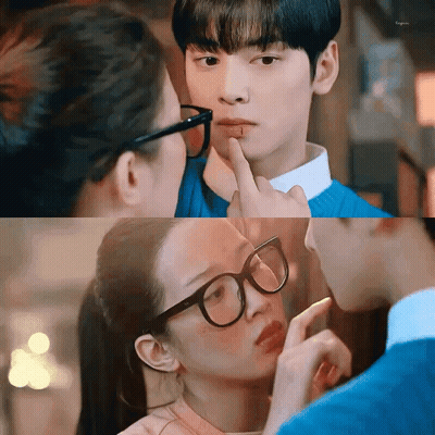 A Woman Wearing Glasses Is Touching A Man 'S Face With Her Finger . GIF
