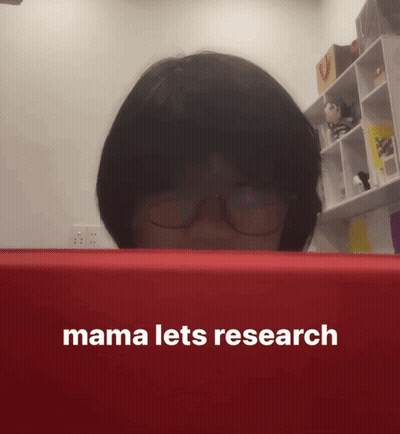 A Woman Wearing Glasses Looks At A Red Box That Says Mama Lets Research On It GIF