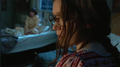 A Woman Wearing Glasses Looks At Something In The Dark GIF