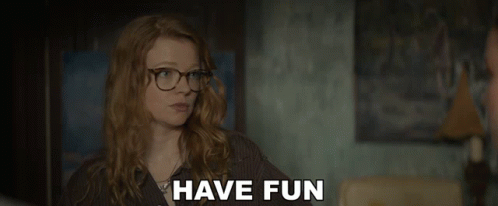 A Woman Wearing Glasses Says " Have Fun " In A Dark Room GIF