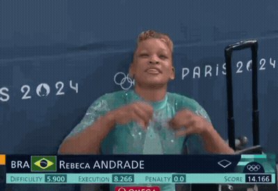 A Woman Wearing Glasses Stands In Front Of A Sign That Says " Rebeca Andrade " GIF