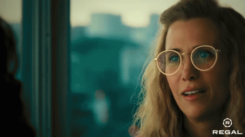 A Woman Wearing Glasses With A Regal Logo On The Bottom GIF