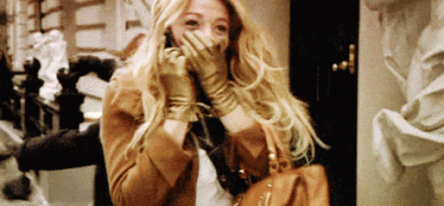 A Woman Wearing Gloves Covering Her Mouth While Holding A Purse GIF