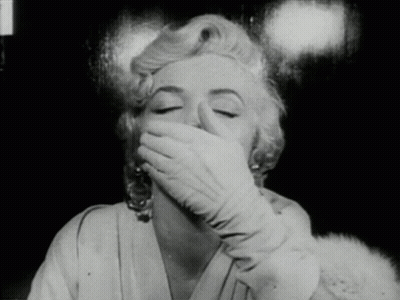 A Woman Wearing Gloves Covers Her Mouth With Her Hand GIF