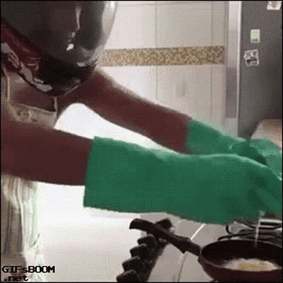 A Woman Wearing Green Gloves Is Cooking On A Stove .. GIF