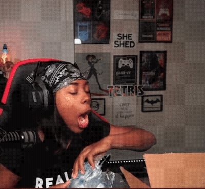A Woman Wearing Headphones And A Bandana Is Sitting In Front Of A Wall With A Sign That Says She Shed On It GIF