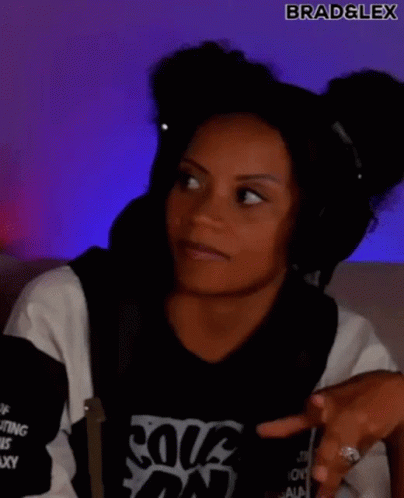 A Woman Wearing Headphones And A Black And White Shirt Is Making A Funny Face . GIF