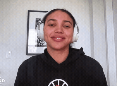 A Woman Wearing Headphones And A Black Hoodie With A Basketball Logo GIF
