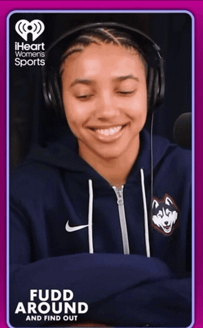 A Woman Wearing Headphones And A Blue Sweatshirt With A Husky On It Is On A Iheart Women 'S Sports Ad GIF